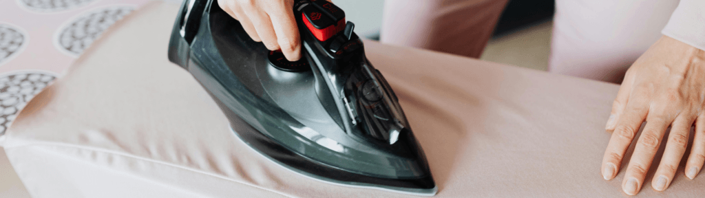Detalhes que fazem diferença Pessoa passando roupa com ferro elétrico, representando cuidado, praticidade e atenção aos detalhes em imóvel de aluguel por temporada.