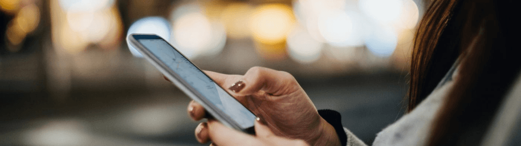 Pessoa segurando um celular e lendo avaliações, representando o impacto de notas medianas no desempenho de anúncios no Airbnb.