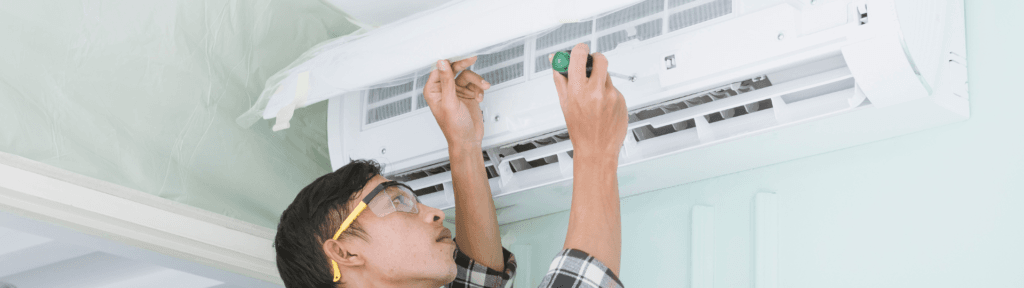 Técnico instalando ar-condicionado em parede interna de apartamento para aluguel por temporada, destacando posicionamento correto do aparelho