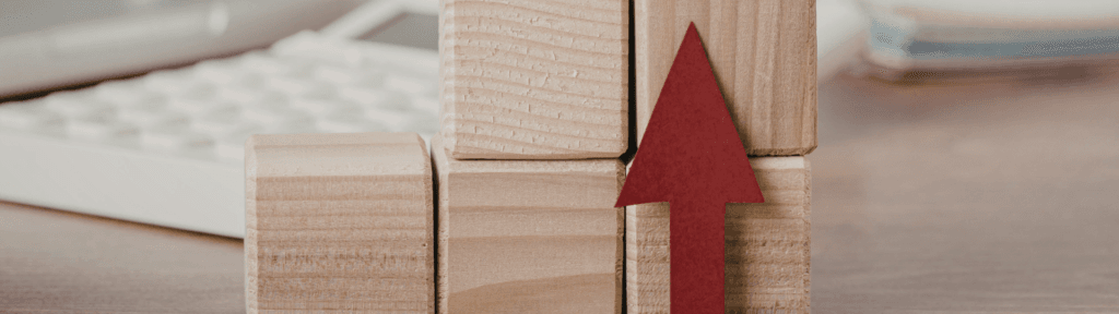 Blocos de madeira com seta para cima representando estratégia de preços no Airbnb para aumentar rentabilidade na baixa temporada